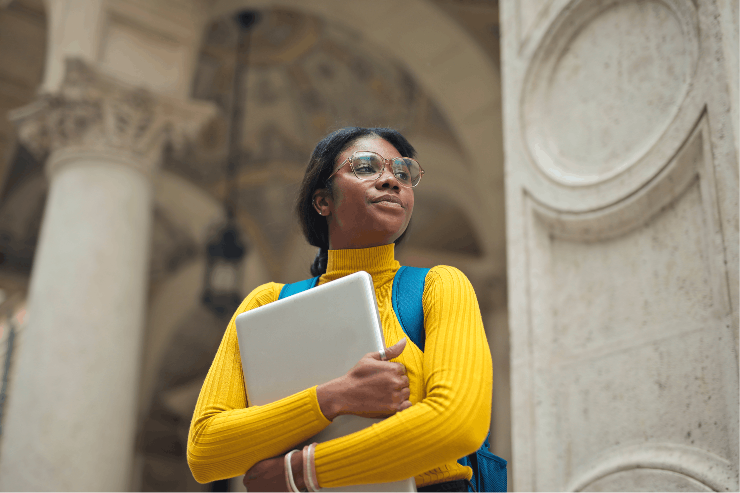 Student holding notebook in front of university