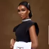 A girl in a black dress carrying a lab coat